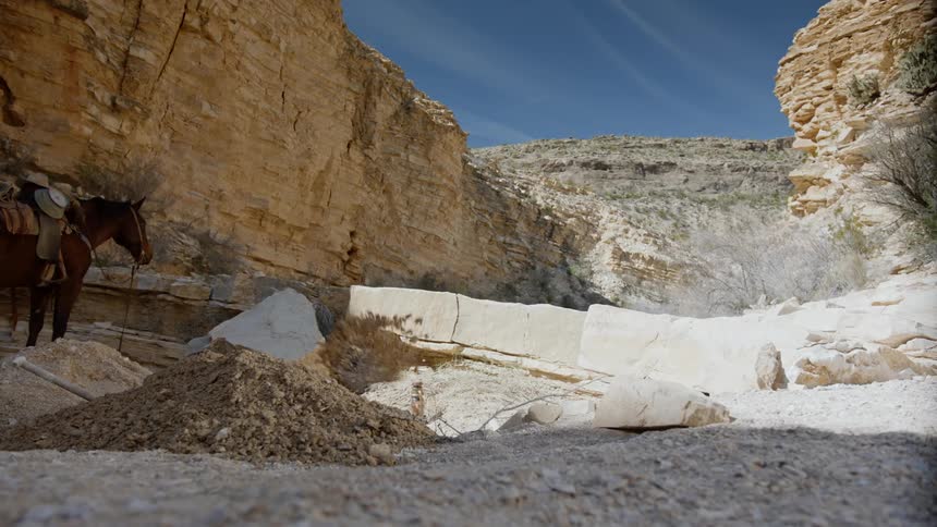 Low angle shot of man digging for treasure in a desert canyon