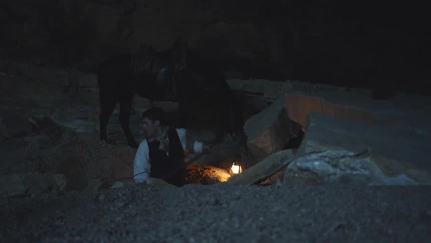 Cowboy digs for gold by lamplight