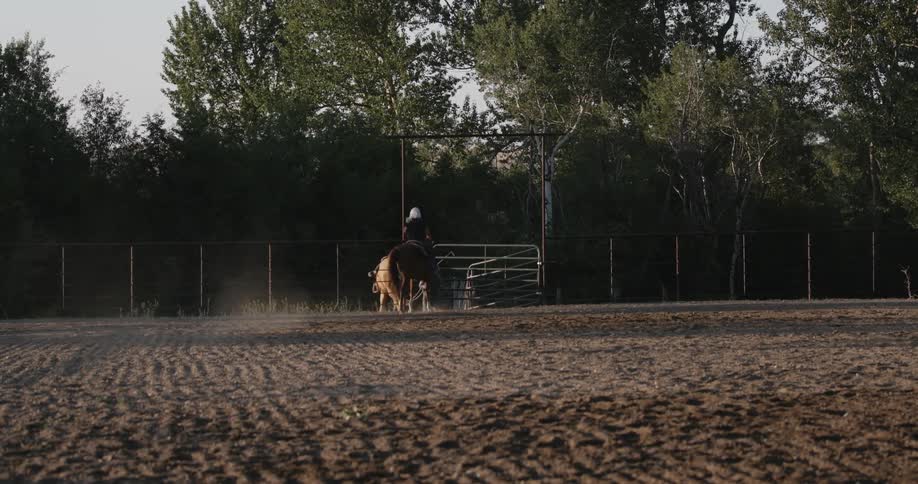 A man walking a horse outside of a fence as a woman rides her horse outside the fence
