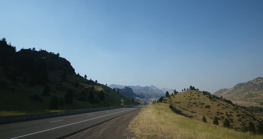 Vehicles driving on a highway through a valley in the mountains at daytime