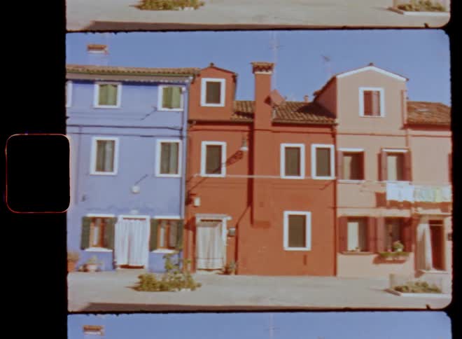 Colorful facades of houses painted blue orange and pink with white window frames near the canals in Venice caught on vintage film