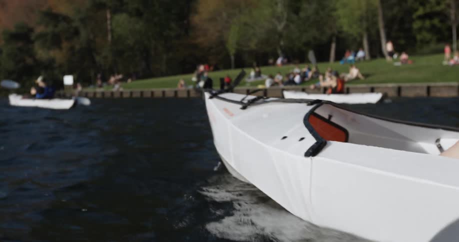 People are rowing in canoes while people watch on the side