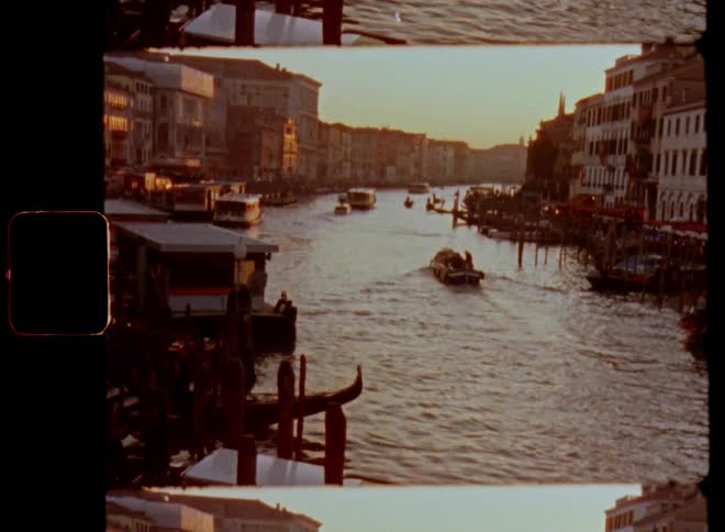 Beautiful evening light shines onto a river or canal in the city or town center of Venice Italy with piers and boats traveling through and seagulls fly and old waterfront buildings and houses stand at the edge of the waterway