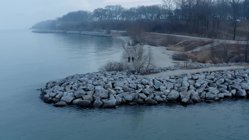 Aerial view of a couple walking near the coast on a park at winter