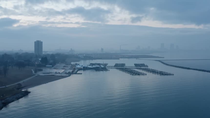 Aerial view of a marina next to the city skyline covered in mist at evening