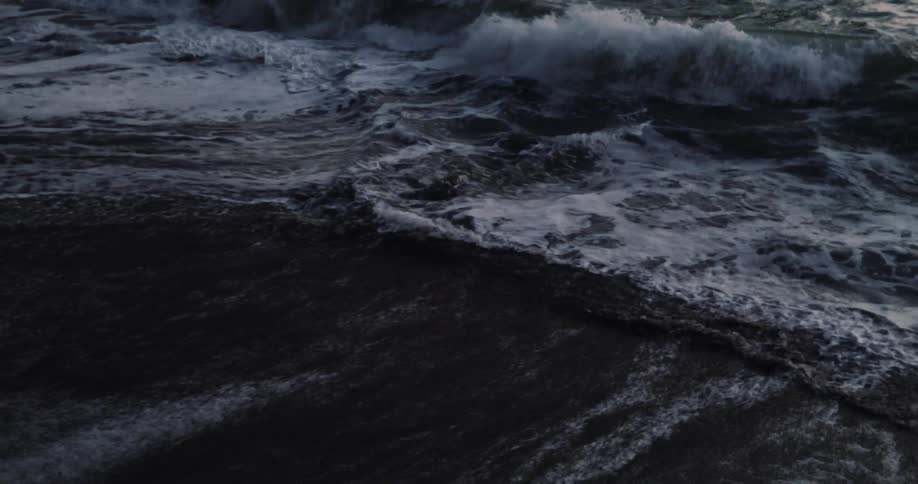 Ocean waves break against the beach at sunset