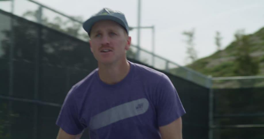 Man playing tennis on an outdoors court at daytime