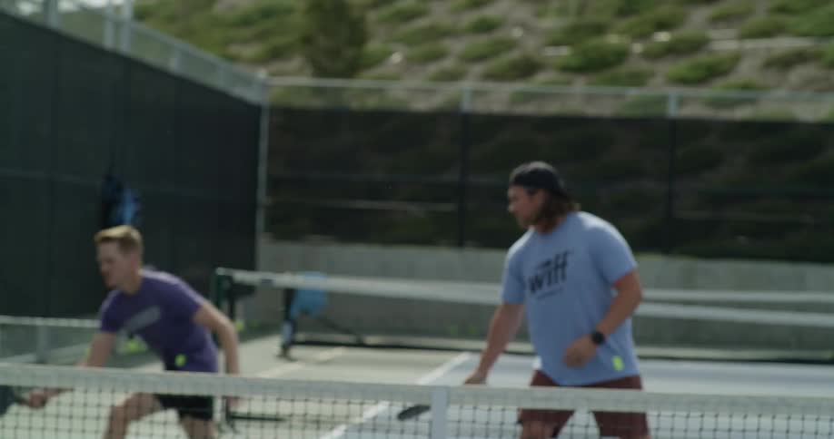 Three men playing paddle ball on an outdoor court