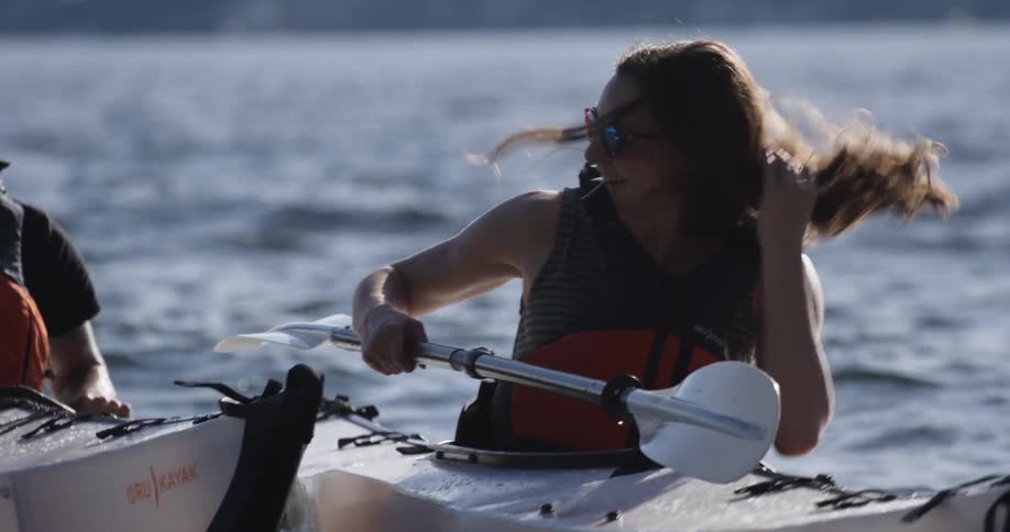 A man and woman on kayaks in the middle of the water