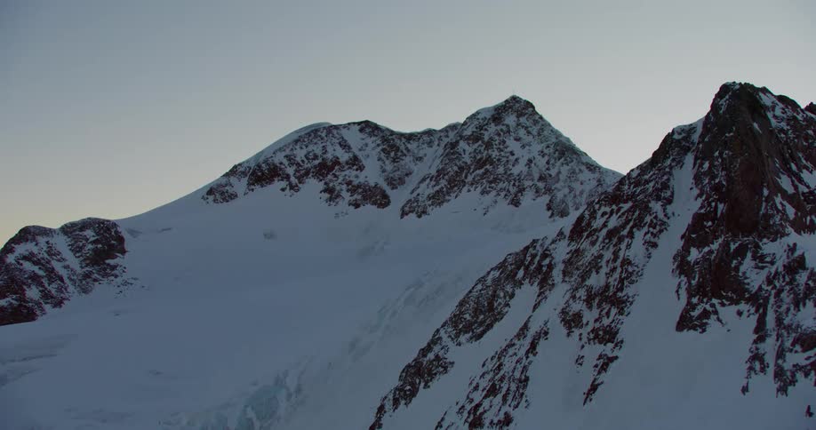 A towering mountain range is covered with a thick layer of snow