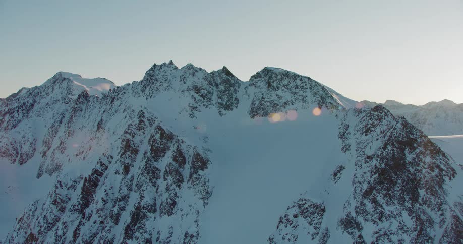 Aerial view of the snow covered slopes of a mountain peak at evening