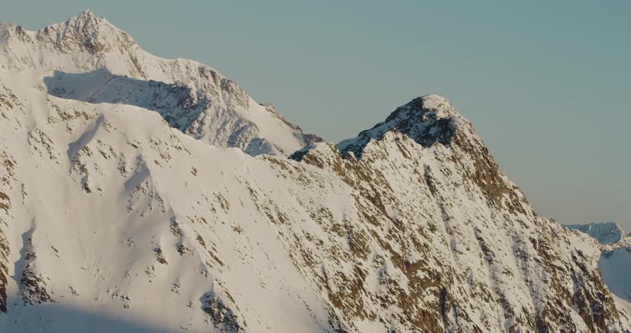 Snow covers the sides of a vast mountain range