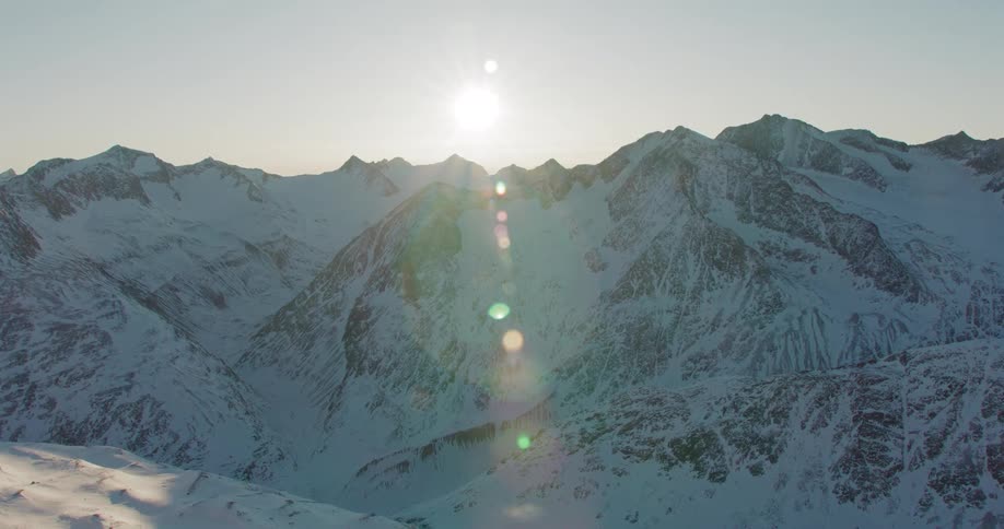 Aerial of snow capped mountain peaks against the sunlight