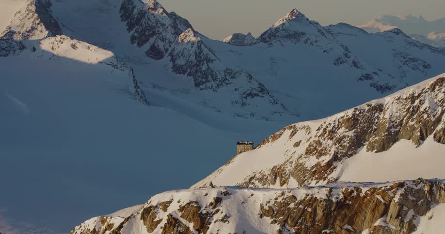A building sits alone on the side of a snow covered mountain