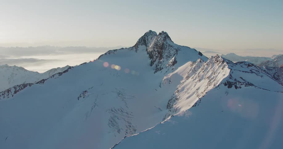 Aerial view coming up on snow covered mountain peak maybe mount fuji