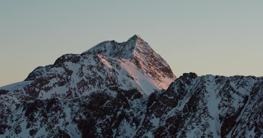 Aerial view of the snow covered slopes of a mountain peak at evening