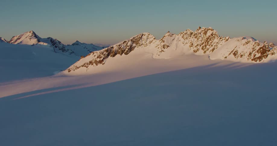 A thick layer of snow coats rocky mountains and the sprawling valleys in between
