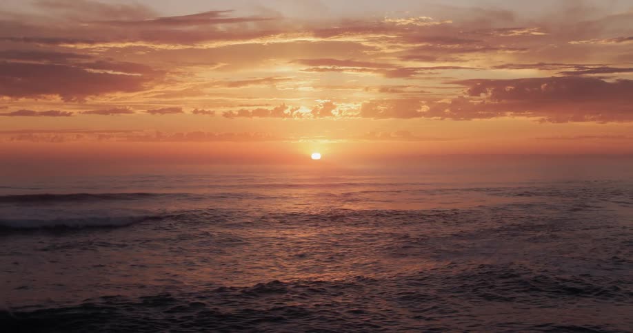 Ocean waves crash to shore at sunset