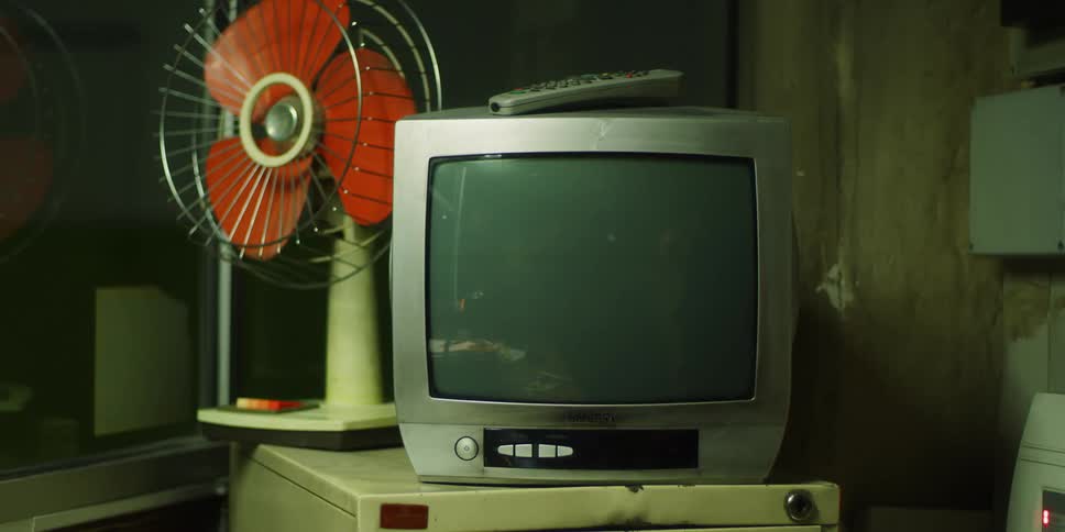 A fan and tv sit on a cabinet