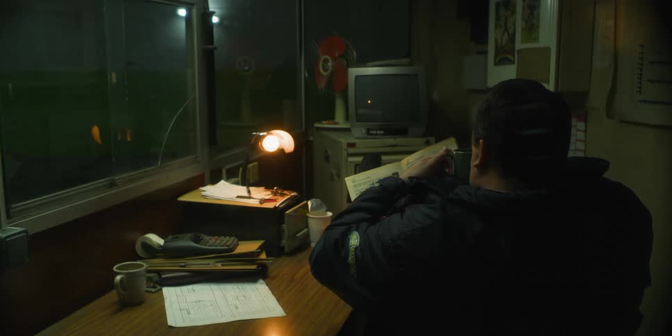 A security guard reads a book in his office