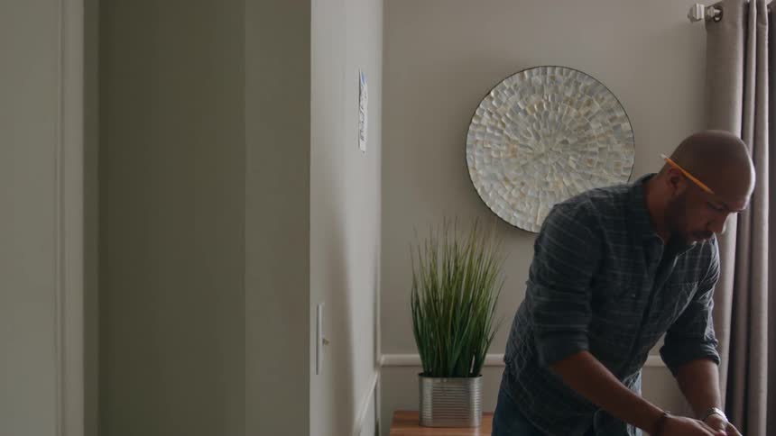 A man tapes a sheet of paper to the wall of an residential home that hes working in