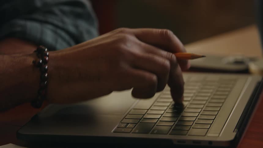 Man sitting at table types on laptop with a single finger