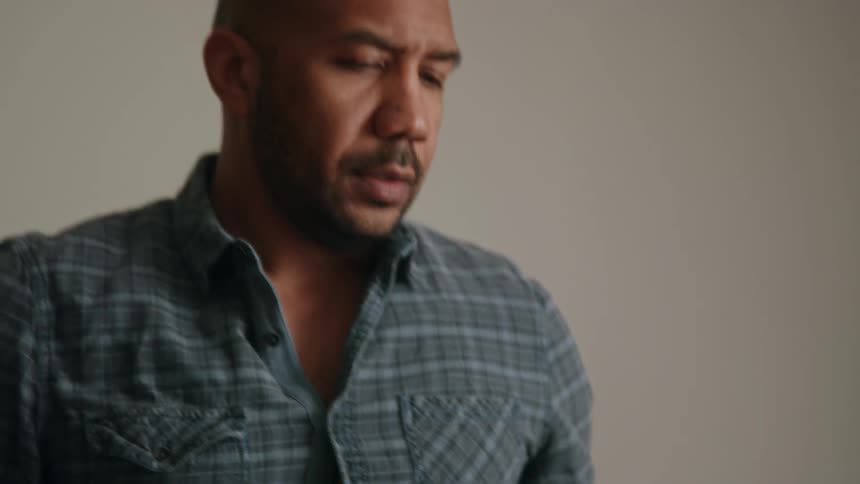 A man leaning on a table then standing up and looking contemplatively and raising his eyebrows
