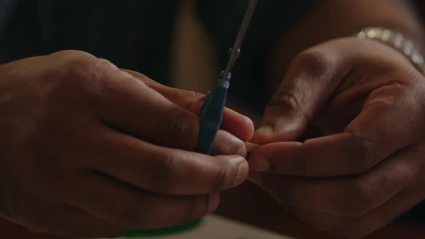 A close up of a persons hands as they use scissors to cut little pieces of paper
