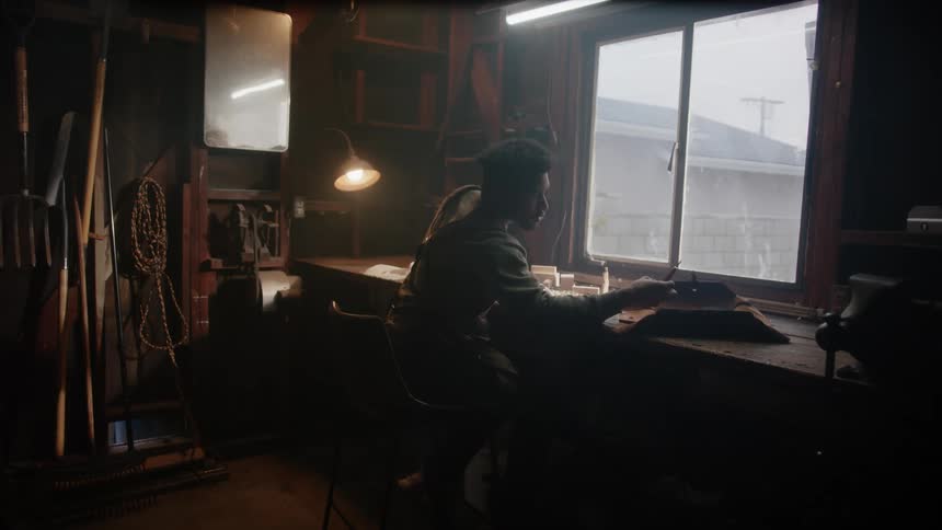 A young black man is inside of his home and building something