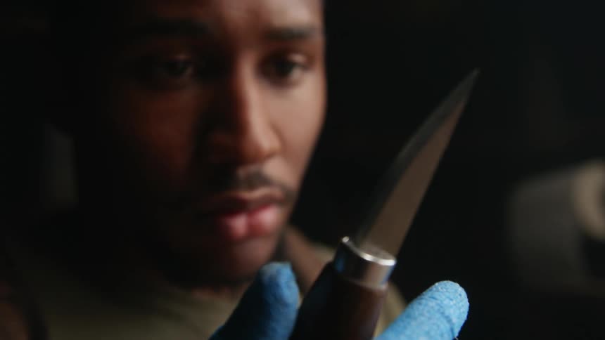 Woodcarver wipes off edge of blade with a hand in a glove