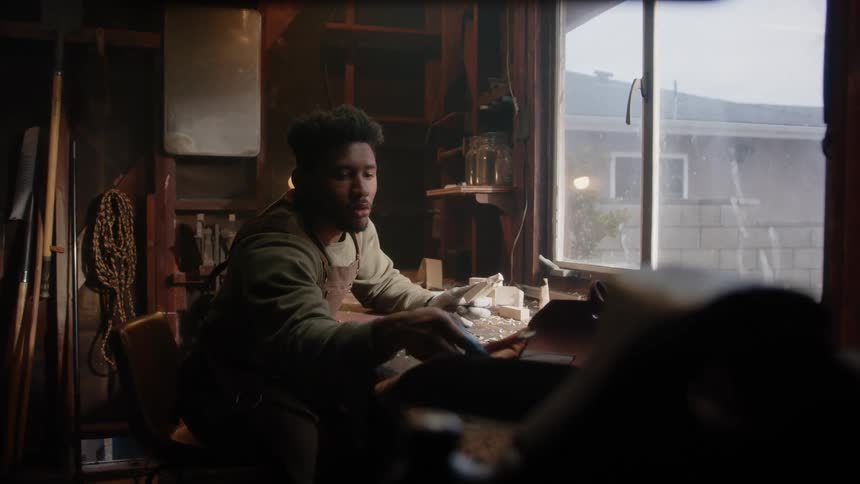A young black man is sitting inside of his home in the day time