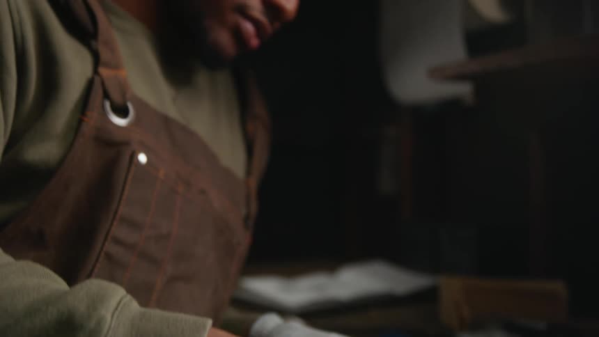 A young black man is indoors and using his tools to fix something