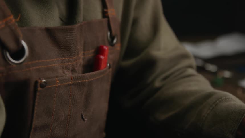 Woodcarver carves piece of wood with a knife while wearing protective gloves