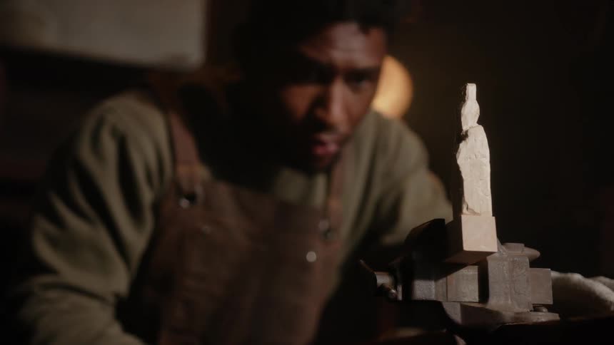 A young black man is sitting down inside of his room