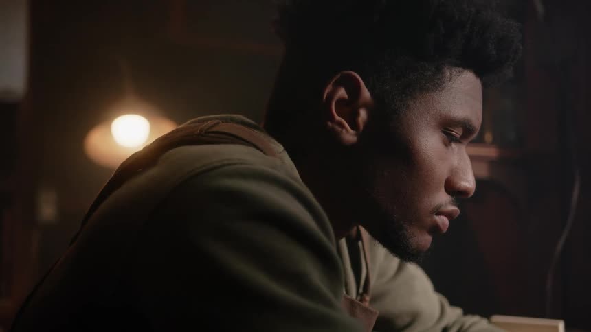 A young black man is sitting down inside of his house
