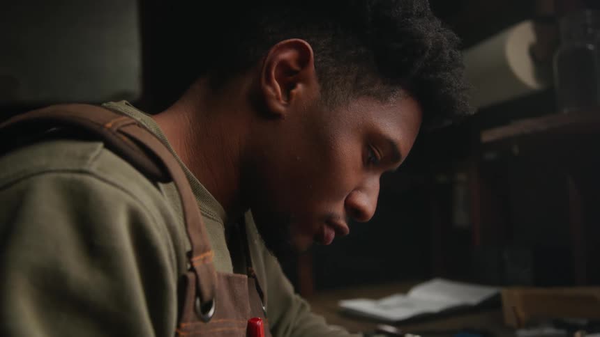 A young black man is building something inside of his home