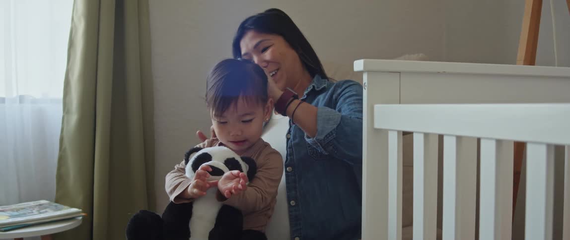 Mother combs the hair of her baby daughter into a ponytail