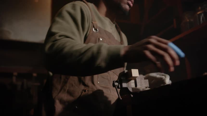 A man standing at a work counter putting wood into a clamp