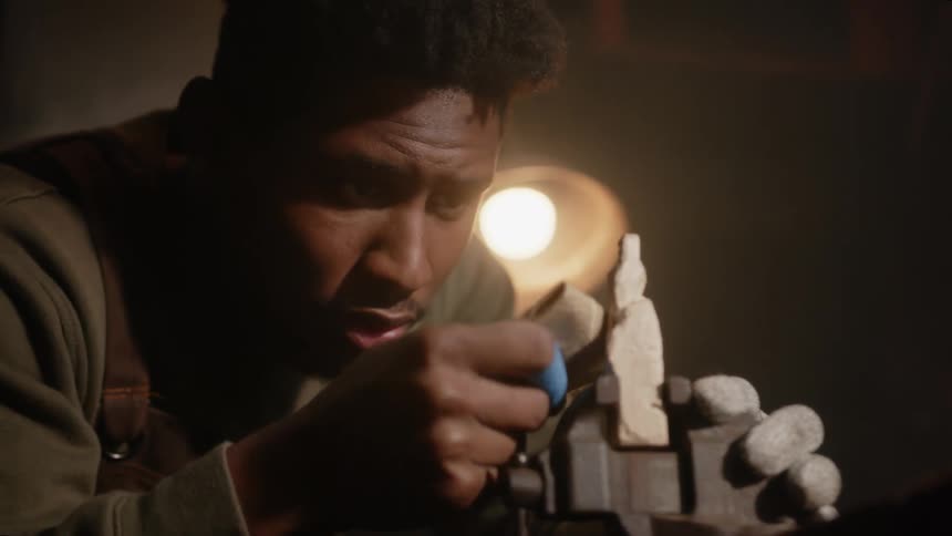 A young black man is making something inside of his house