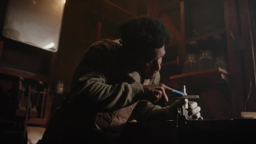 A young black man is fixing something inside of his home