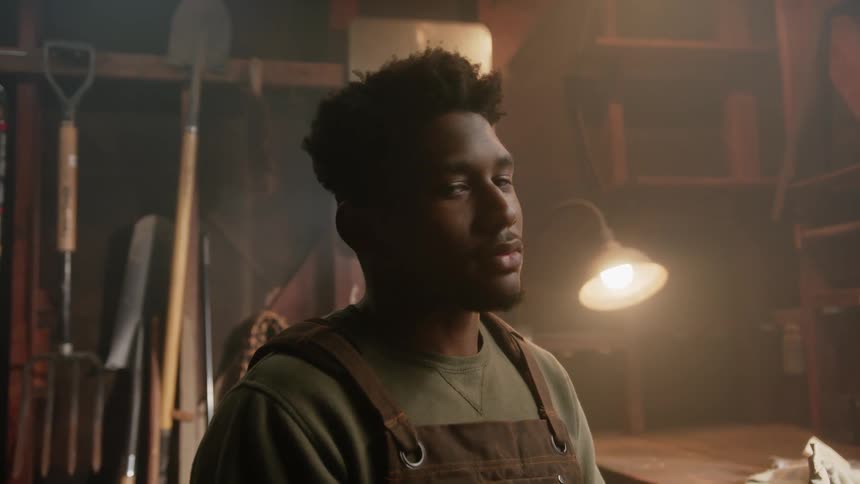 A young black man is indoors and posing for the camera