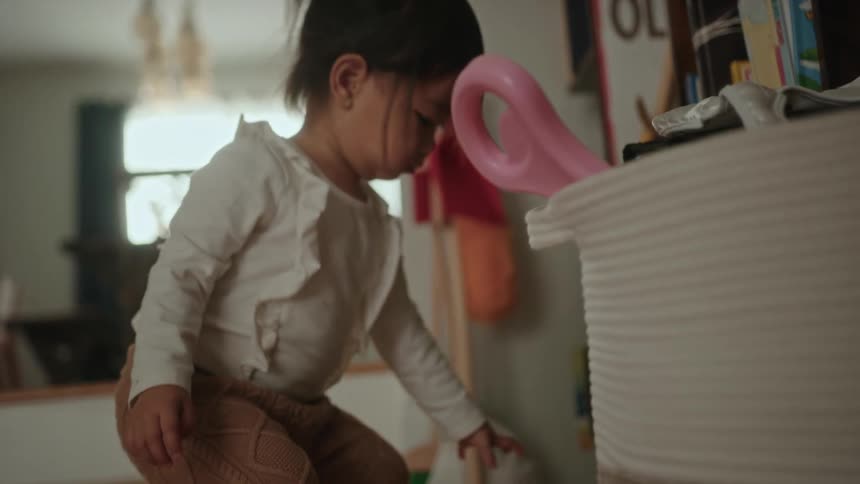 Young child crouches down near bookshelves