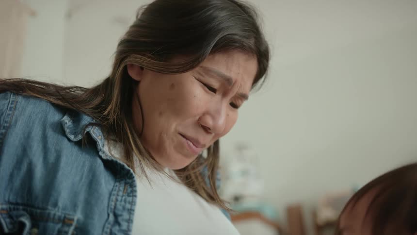 Mother smiles as child places her head against mothers pregnant belly