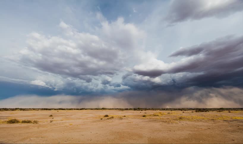 Dust storm forming under white clouds in the sky