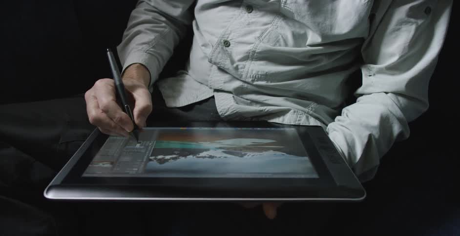 A man edits a photograph on a tablet using a stylus
