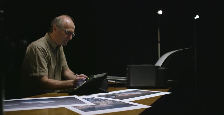 A man works at a desk using a tablet to edit photos