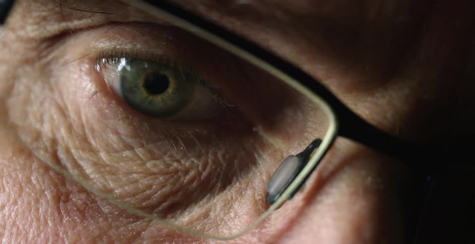 A man's eye peers through his glasses