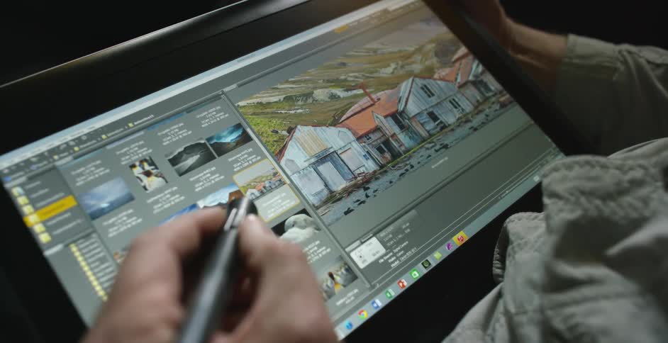 A man uses a pen and tablet to review photographs