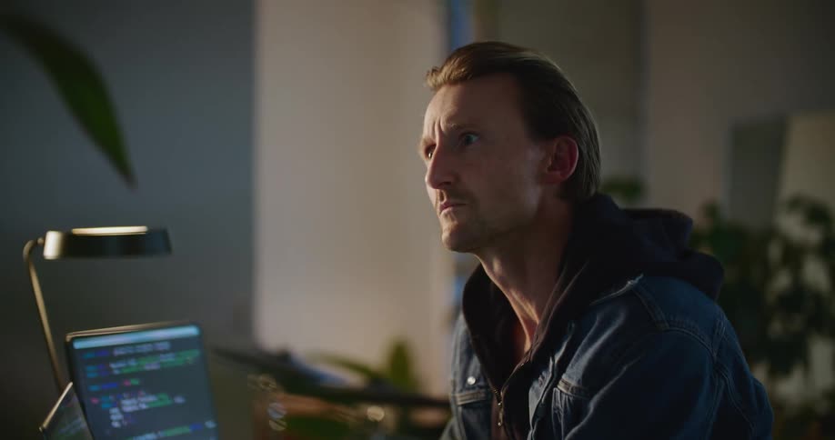 Man types on laptop taking a moment to think