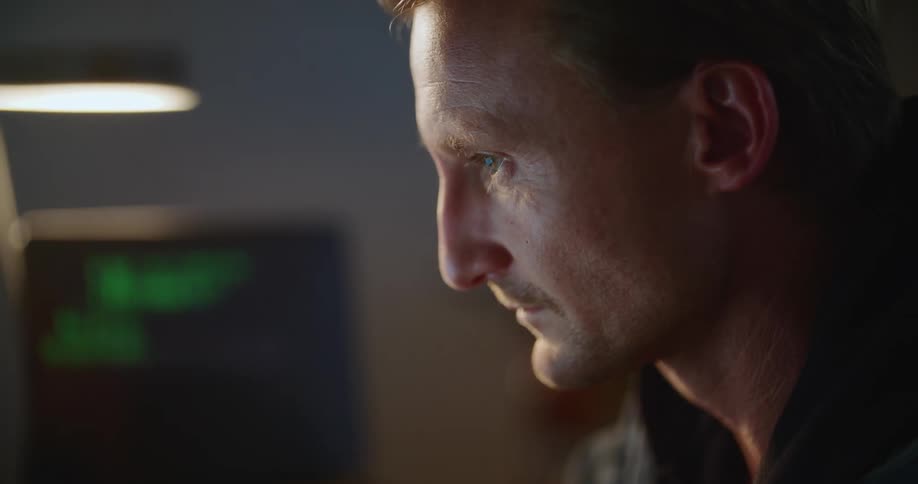 Man working with two computers in office rubs his eyes